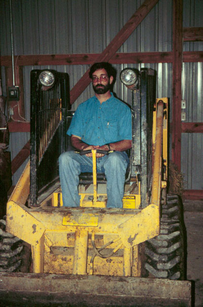 Photo of FACE investigator sitting in skid-steer loader with modified ROPS 