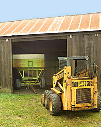 Photo of skid steer loader near doorway of machine shed